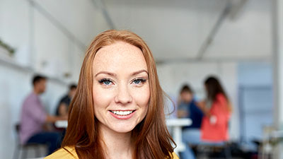 Student smiling while classmates are sitting at desks