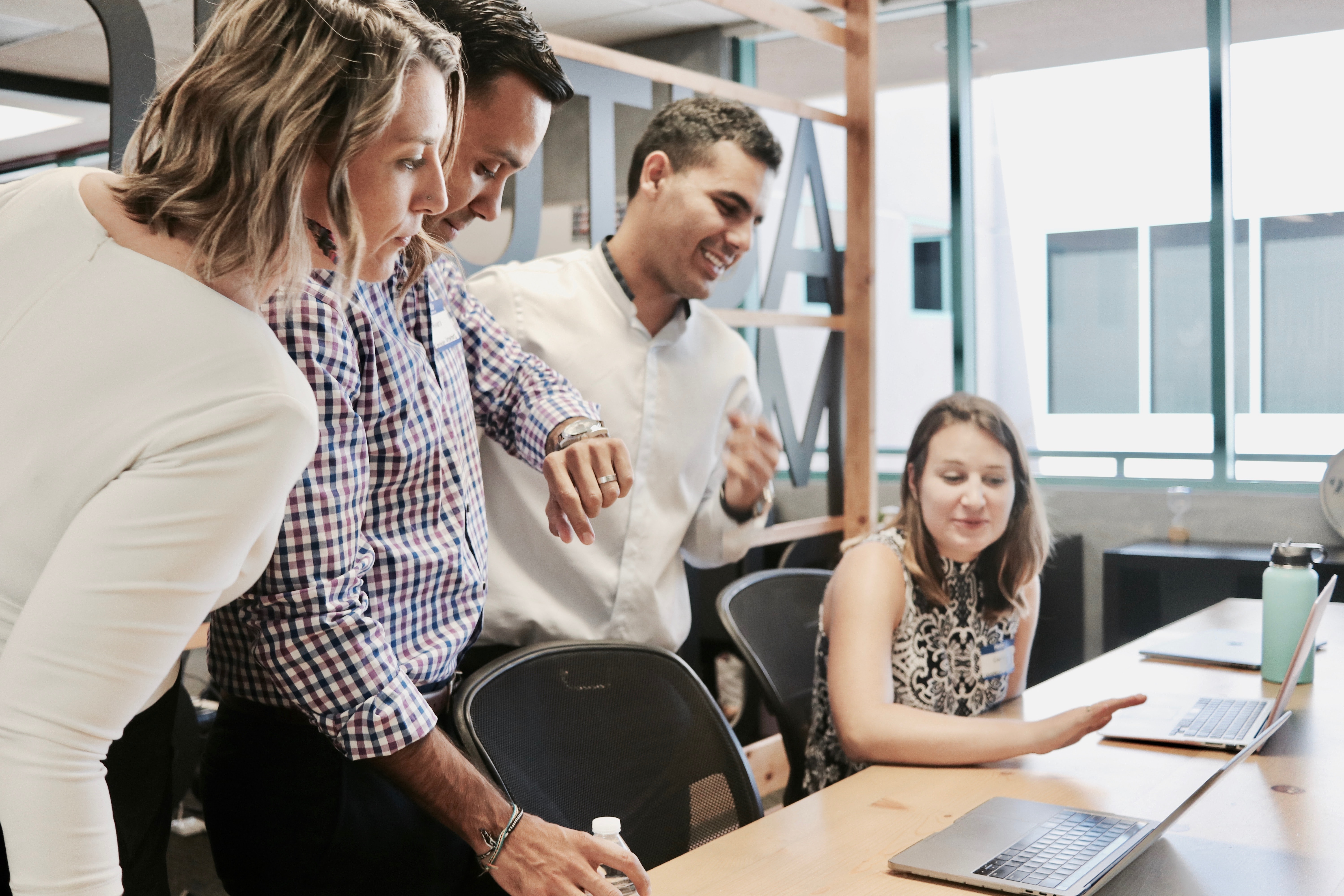 A group of four business professionals looking at a laptops