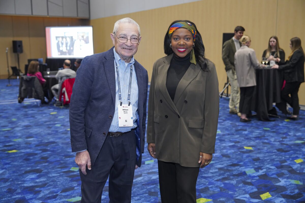 Two SIOP members standing together in front of a vibrant blue carpet.