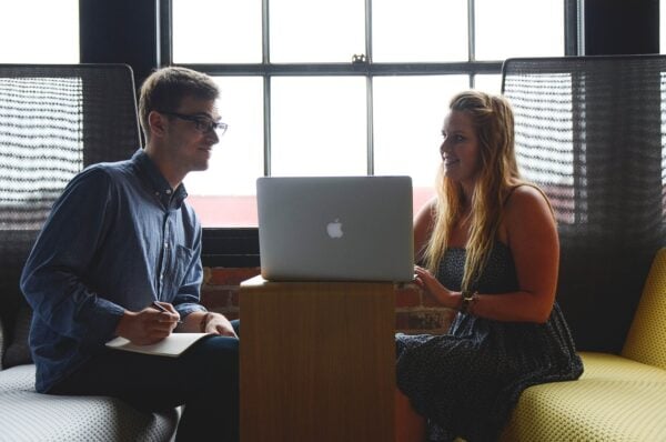 two people talking with a laptop in between them