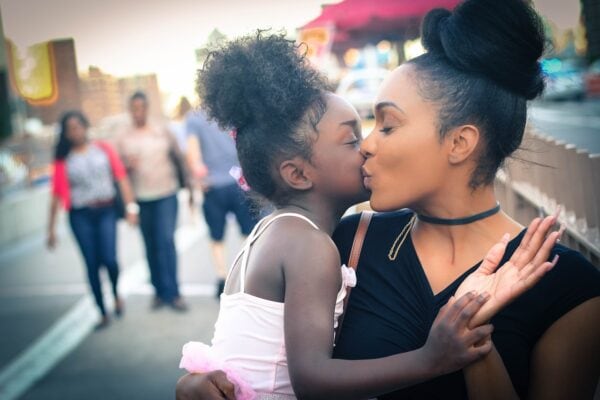 mom kissing daughter on cheek