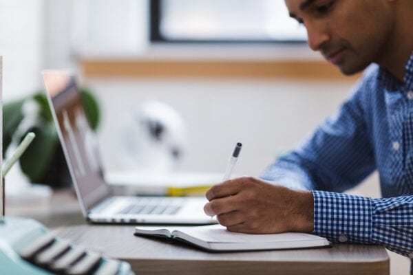 man writing on a notepad