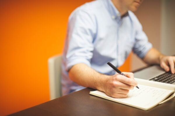 man writing on a notepad