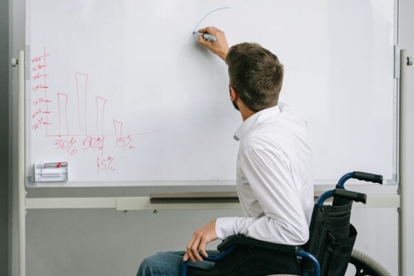 man in wheelchair writes on a whiteboard