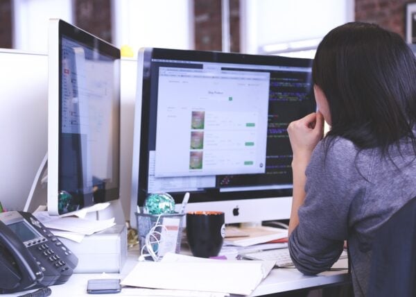 woman behind a desk looking at desktop screen