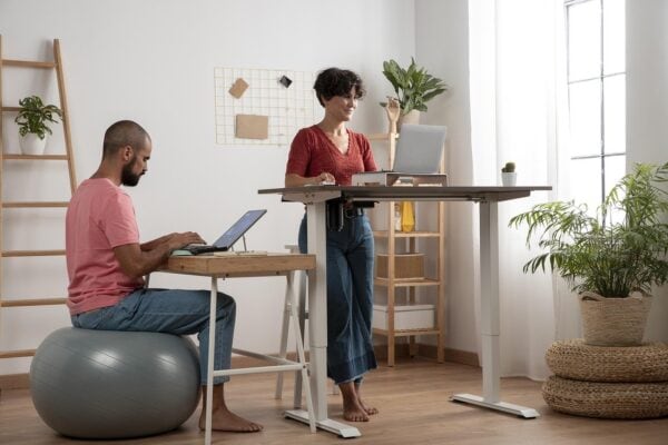 woman working at a standing desk and man sitting on exercise ball