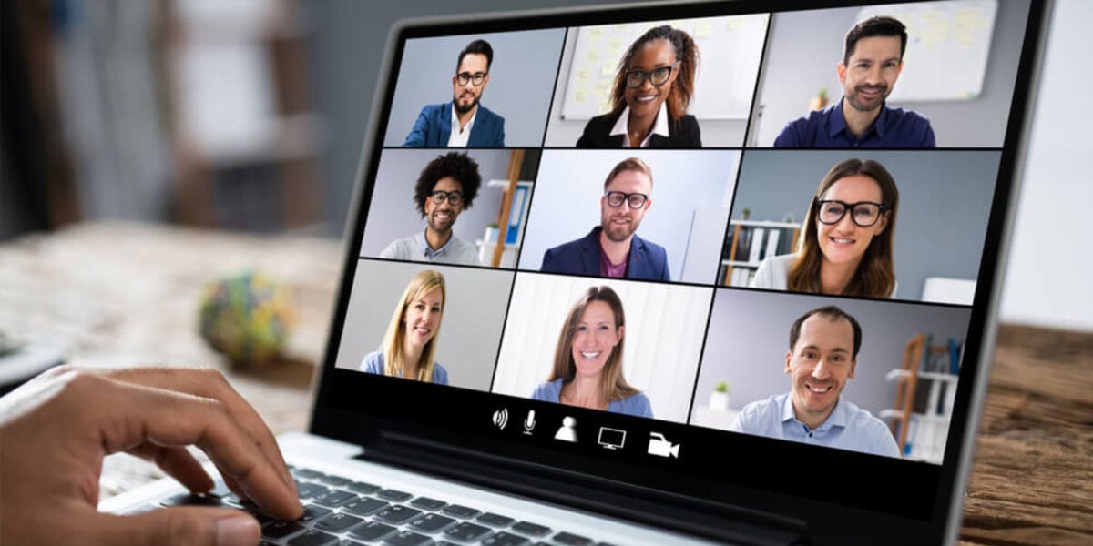 Individual participating in a video conference on a laptop, attentively interacting with others on the screen.