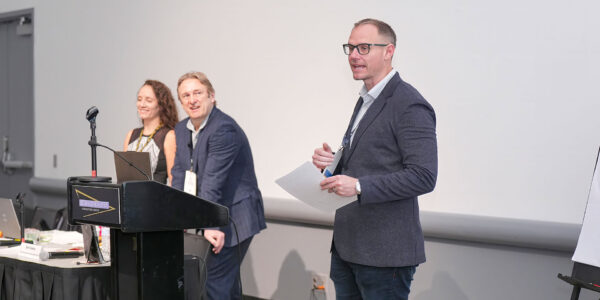 Three people are positioned at a podium, utilizing a laptop for a presentation at one of the SIOP Annual Conferences.