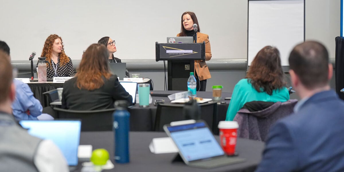 A woman presenting to an audience, engaging them with her speech and visual aids.