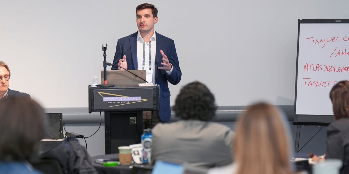 A man delivers a presentation to a captivated audience, highlighting key points with gestures.