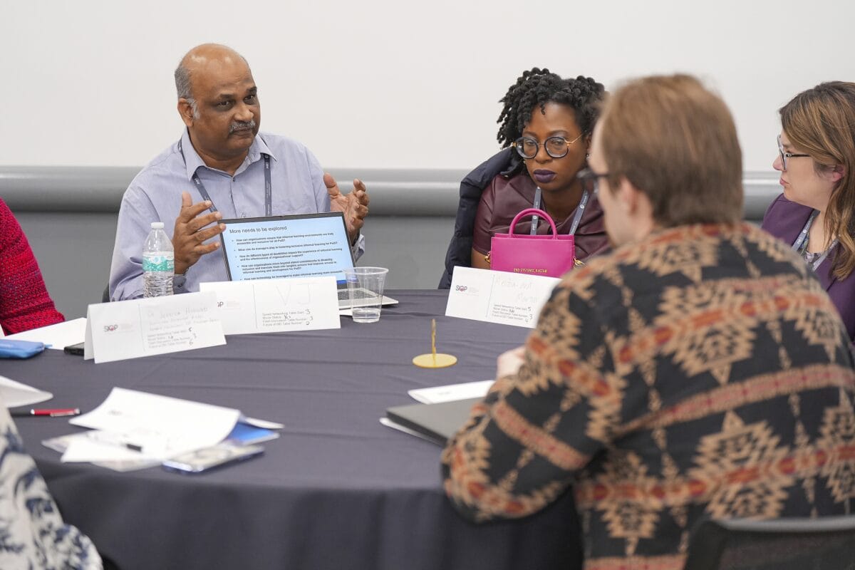 A diverse group of people collaborating while sitting in chairs around a table.
