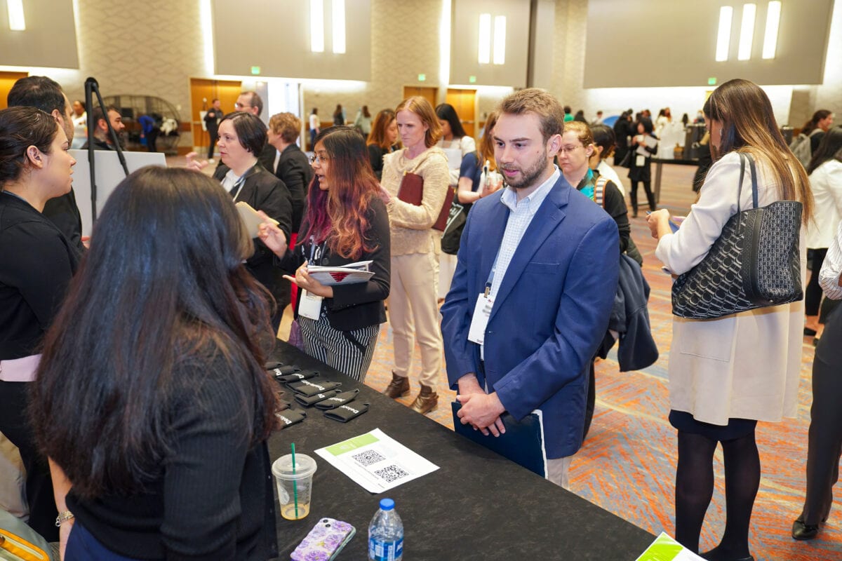 A diverse group of people gathers around a table, discussing opportunities and sharing resumes.