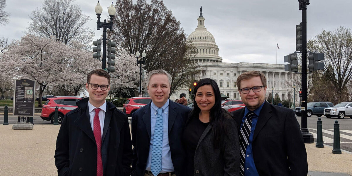 Four I-O professionals standing and posing for a photo outside the U.S. Capitol building.