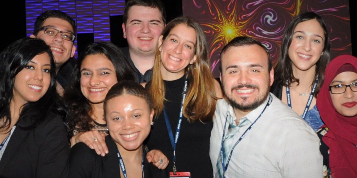 A diverse group of people smiling and posing together for a photo at a lively event.