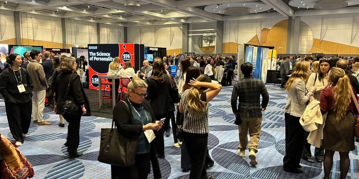 A diverse group of attendees standing together in a bustling convention hall, surrounded by booths and displays.