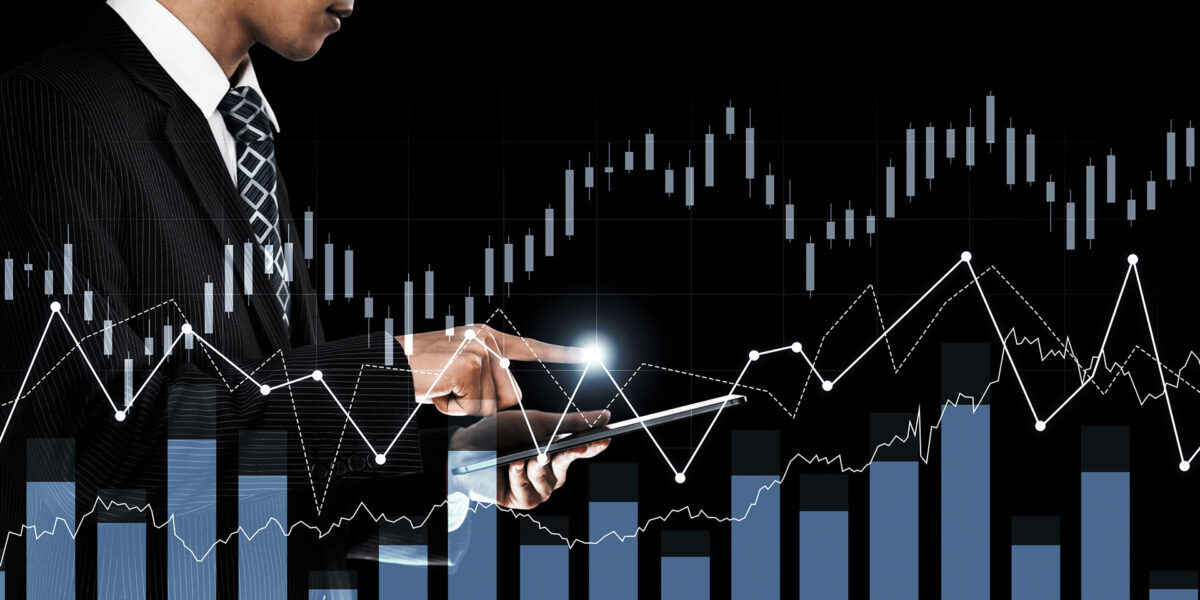 A man in a suit holds a tablet displaying a graph, indicating data analysis or business performance.
