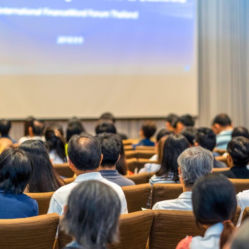 Back side of audience listening the Speaker with podium on the stage in the conference hall