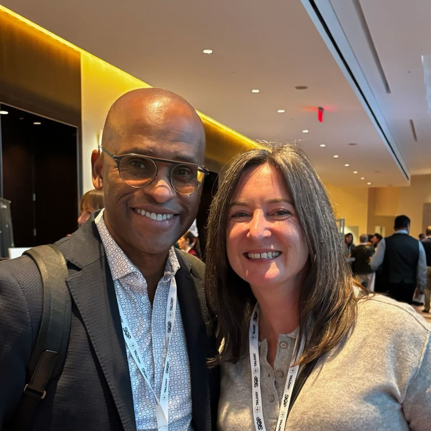 A man and woman smiling at the camera in a stylish hotel lobby, showcasing a warm and welcoming atmosphere.