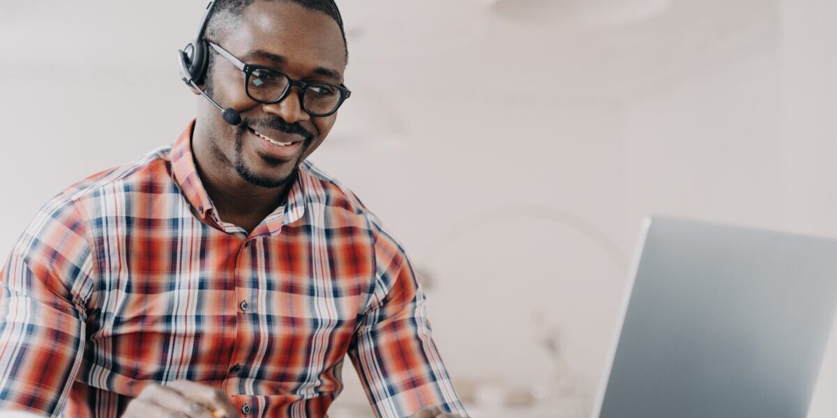 Smiling man in wireless headset sits at desk