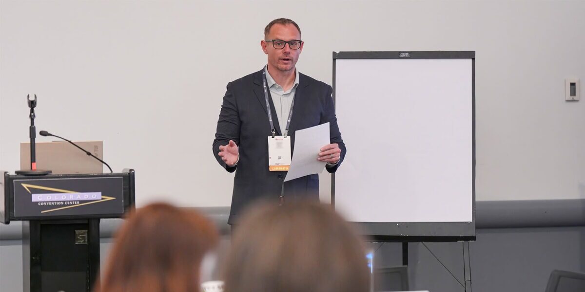 A man in a suit giving a presentation to a group of people.