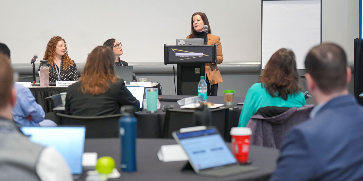 A woman presenting to an audience, engaging them with her speech and visual aids.