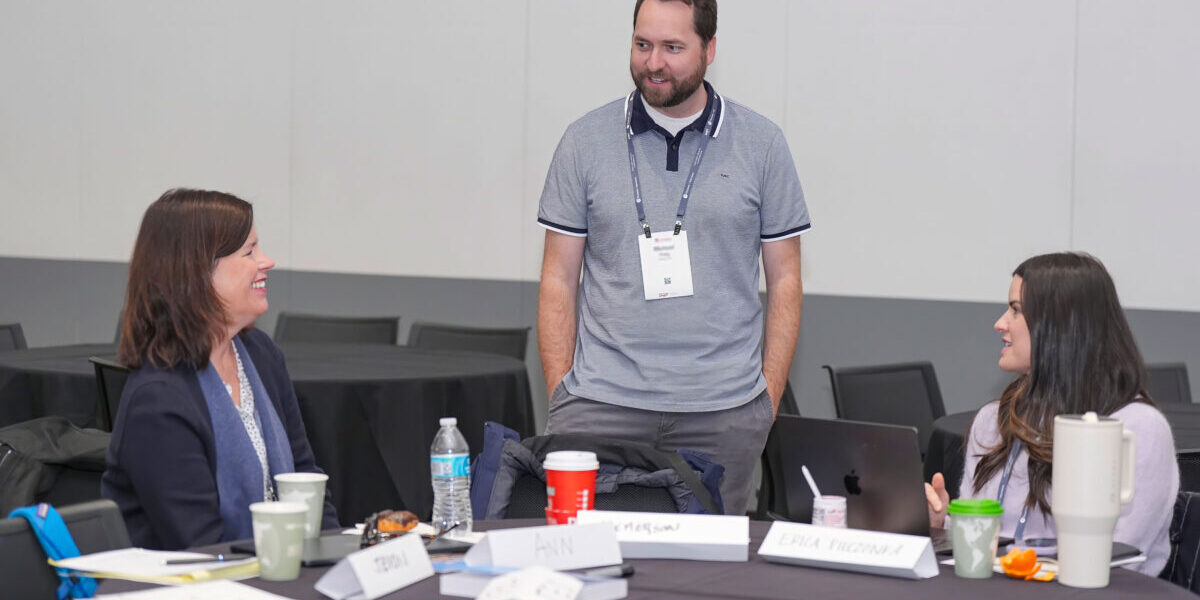 An industrial-organizational psychologist discusses ideas with colleagues at a professional conference.
