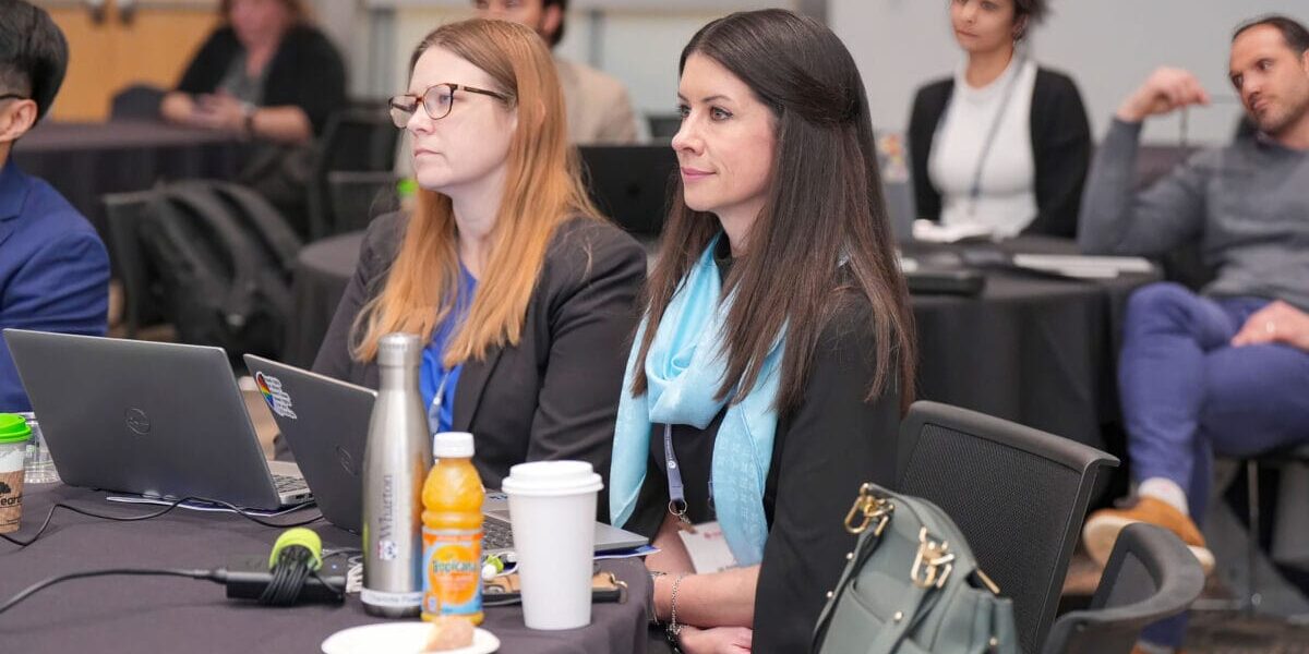A group of diverse individuals seated at a table, each using a laptop during one of SIOP's annual conferences.