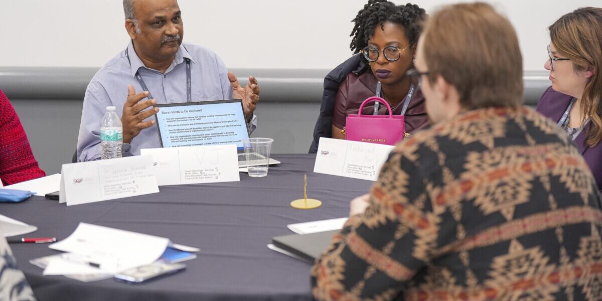 A diverse group of people collaborating while sitting in chairs around a table.