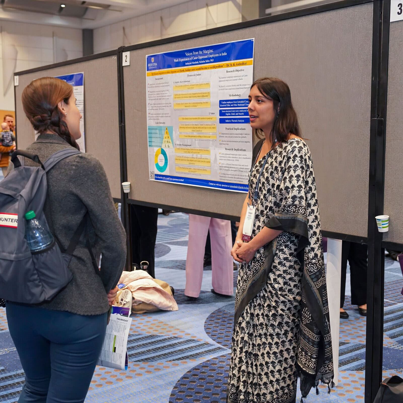 Woman presenting at SIOP conference with audience in front of poster.