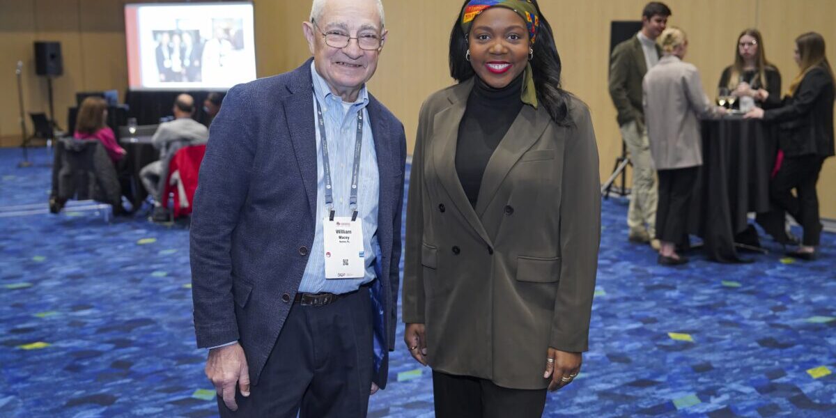 Two SIOP members standing together in front of a vibrant blue carpet.