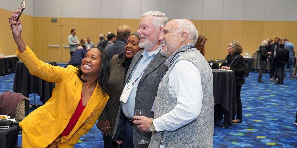 A group of SIOP Annual Conference attendees, all smiling, in a lively conference room with colorful decorations.