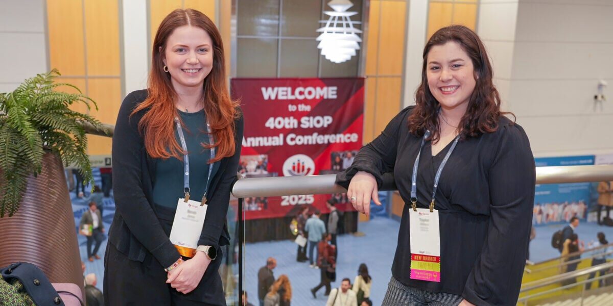 Two women standing next to each other in an indoor lobby.