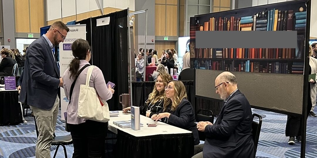 A table with people engaging, surrounded by books displayed on the wall behind them.