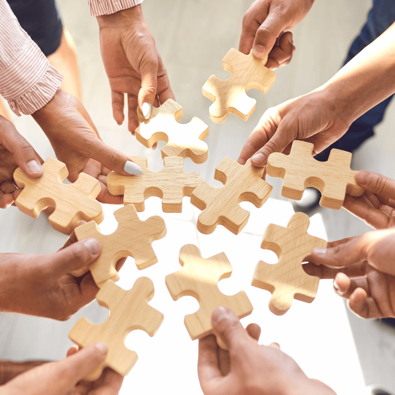 a group of people holding wooden puzzle pieces together