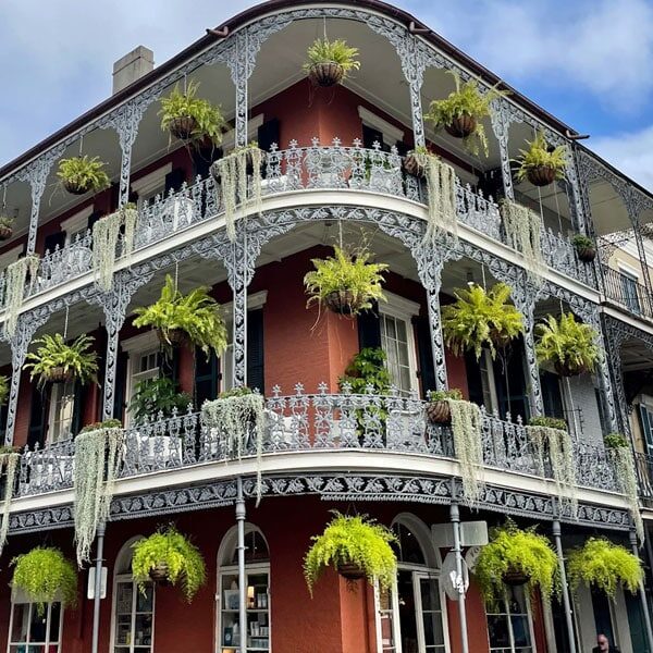 An elegant building with decorative balconies, each filled with lush greenery and vibrant plants.