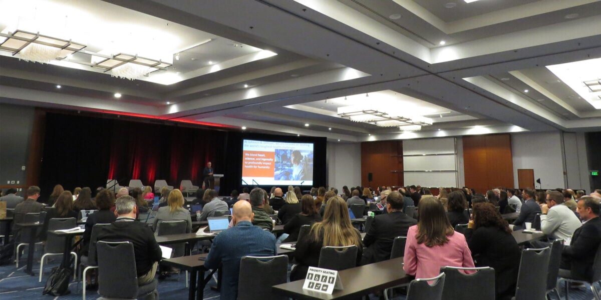 A spacious room filled with people seated at tables, engaged in conversation and activities.