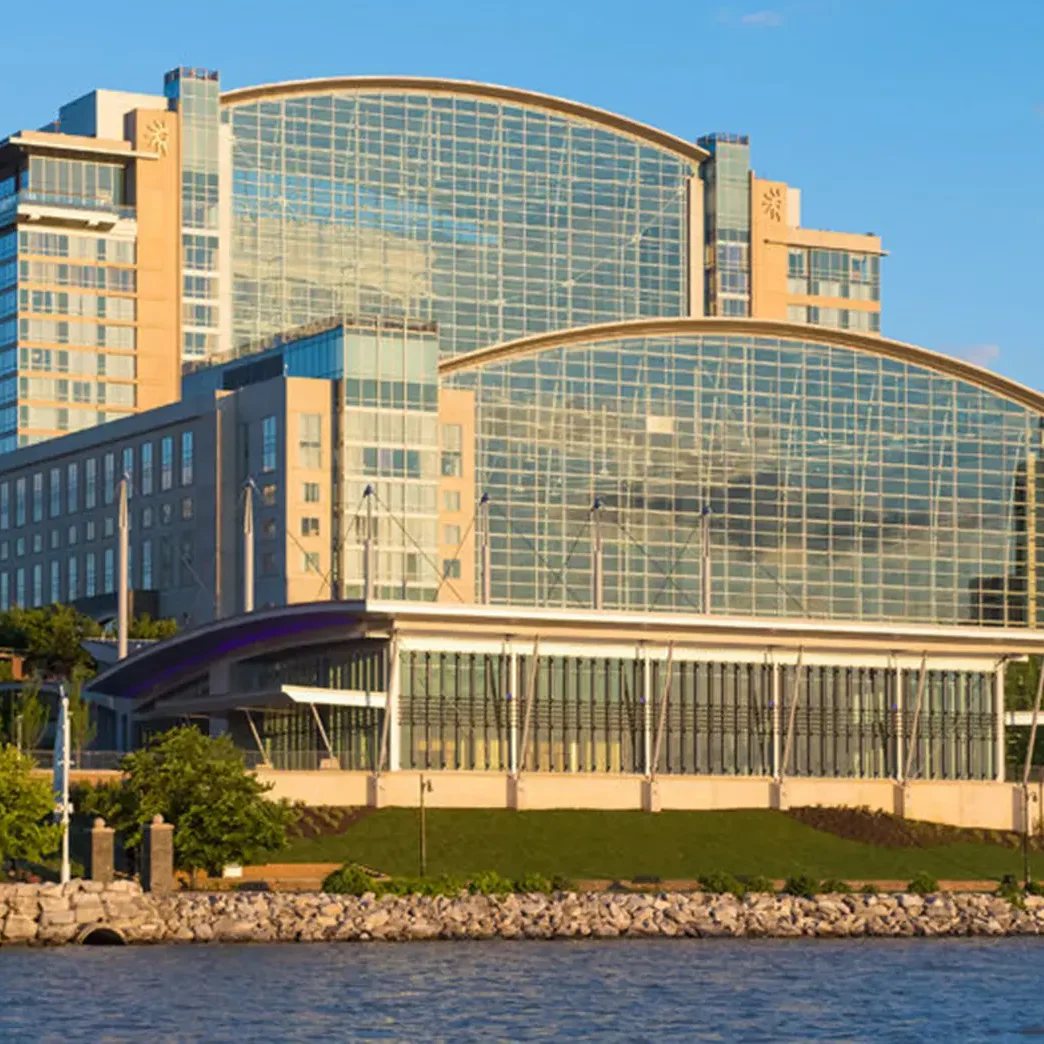 Modern conference center with glass facade near water and green landscape.