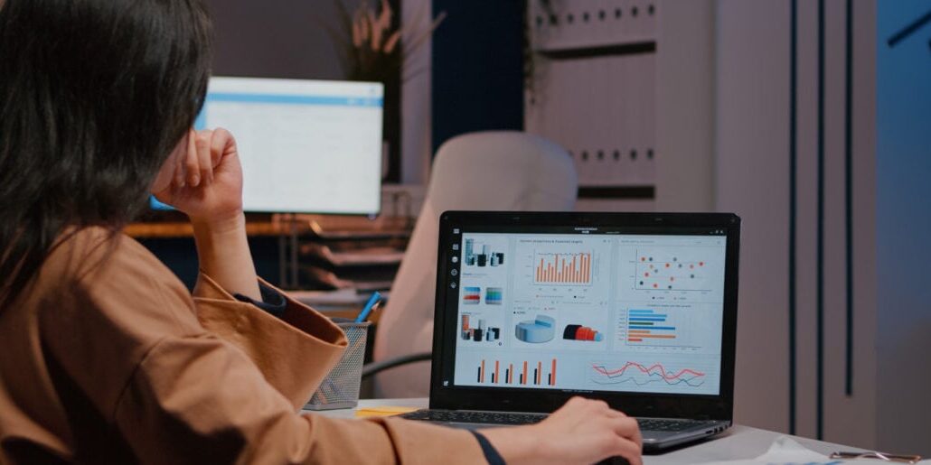 woman typing at computer showing graphs and tables