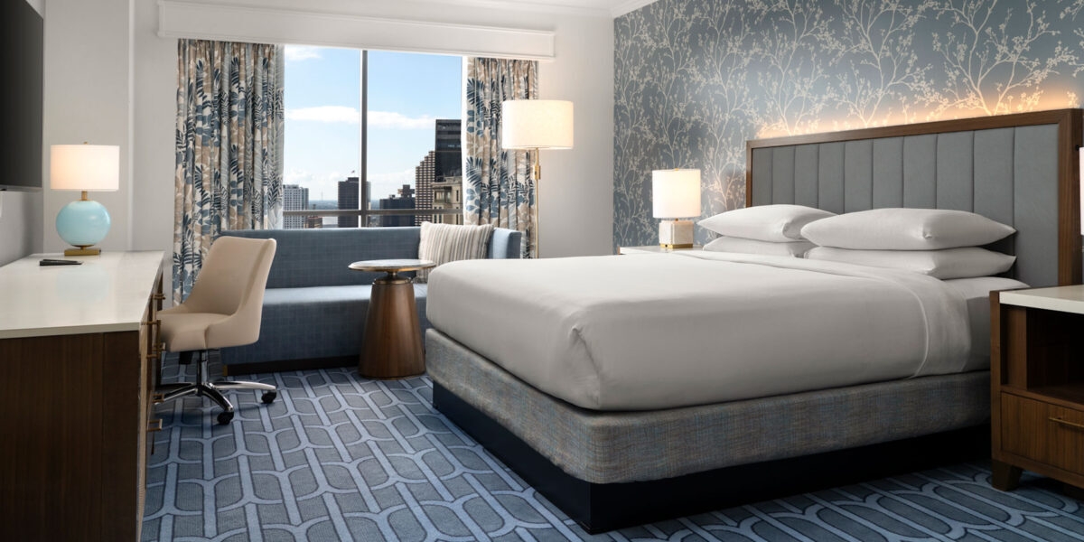 A hotel room with a bed, desk and chair.