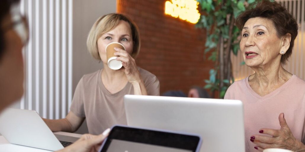 Senior women working on laptops at coffee shop