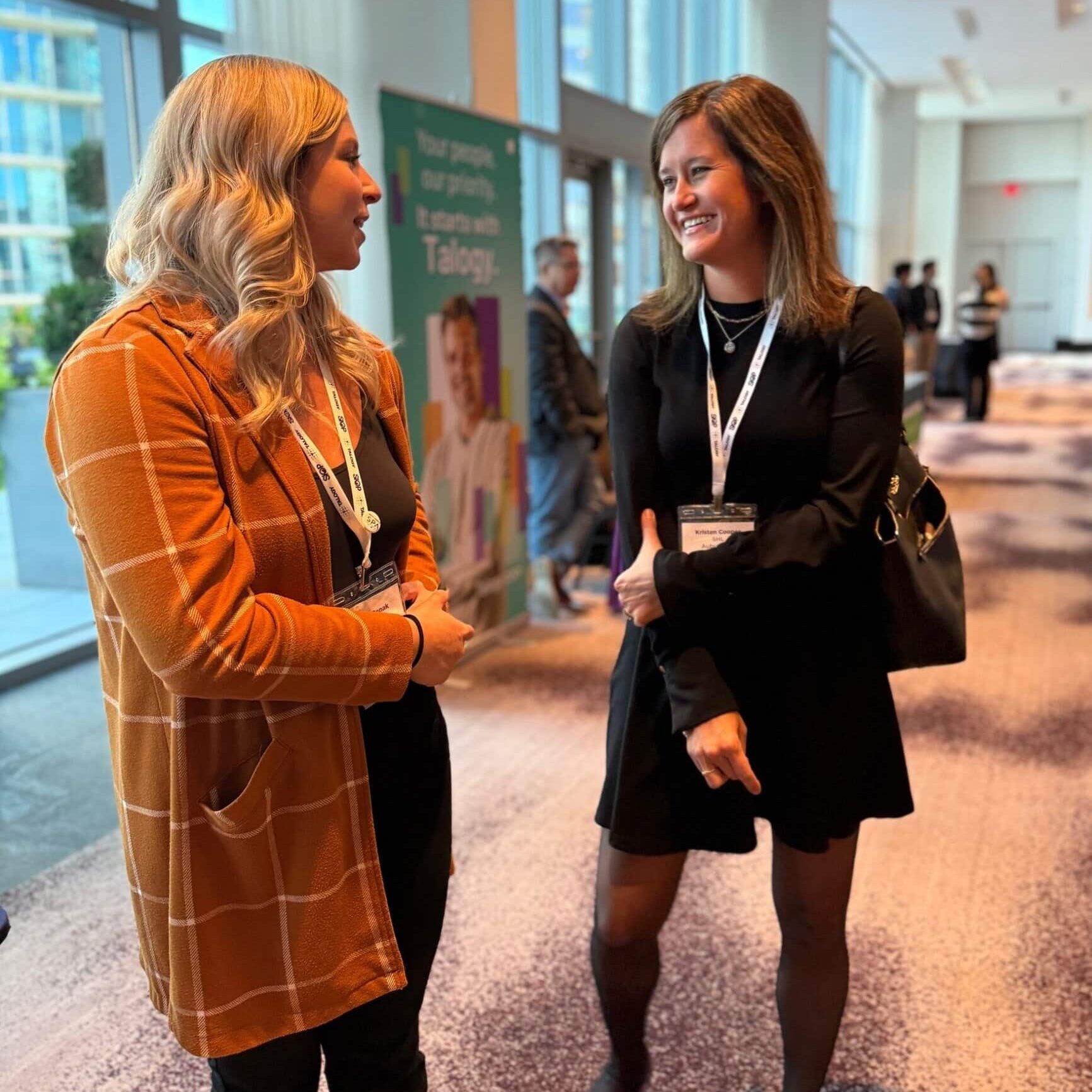 Two women talking in a spacious lobby, surrounded by comfortable seating and contemporary decor.